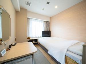 熊本市にあるNatural Hot Spring SUPER HOTEL Kumamoto Chamber of Commerceのベッドと机があるホテルの部屋