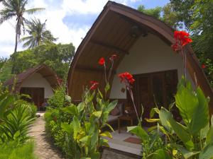 une petite maison avec des fleurs rouges devant elle dans l'établissement Chill Out Bungalows, à Gili Air