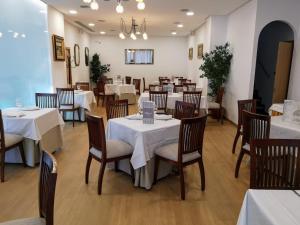 un comedor con mesas y sillas blancas en Hotel Abadi en Córdoba