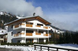 a white building with wooden balconies in the snow at Villa Aylin in Prato alla Drava
