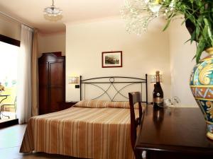 ein Schlafzimmer mit einem Bett und einem Tisch mit einer Vase in der Unterkunft Villa Cristina in Giardini-Naxos