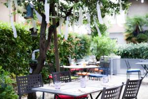 a group of tables and chairs under a tree at Locanda Alla Mano in Forlimpopoli