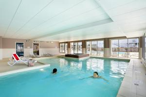 two people swimming in a large swimming pool at Résidence Goélia Les Balcons des Pêcheurs in Mimizan-Plage