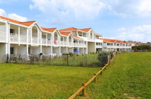 una fila de casas blancas con techos rojos en Résidence Néméa Les Balcons des Pêcheurs, en Mimizan-Plage