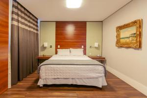 ein Schlafzimmer mit einem großen Bett und zwei Nachttischen in der Unterkunft Tri Hotel Executive Criciúma in Criciúma