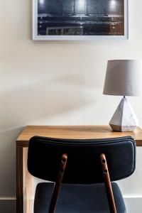 a chair in front of a wooden desk with a lamp at Found Hotel Boston Common in Boston
