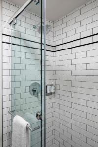 uma casa de banho com uma cabina de duche em vidro com azulejos brancos em Found Hotel Boston Common em Boston