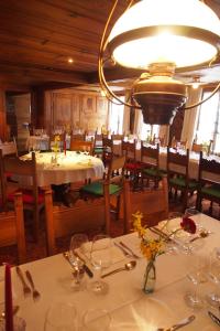un restaurante con mesas y sillas blancas y una lámpara de araña en Hotel Simmental, en Boltigen