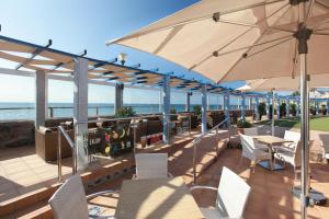taras ze stołami, krzesłami i parasolem w obiekcie Grupotel Playa Feliz w mieście San Agustin