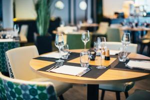 a wooden table with wine glasses and napkins at Hôtel Restaurant Athena Spa in Strasbourg