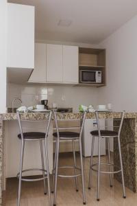 a kitchen with three bar stools and a counter top at Star Apart Hotel in Teófilo Otoni