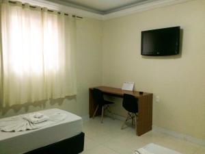 Habitación con escritorio y TV en la pared. en Rouge Hotel, en São Paulo