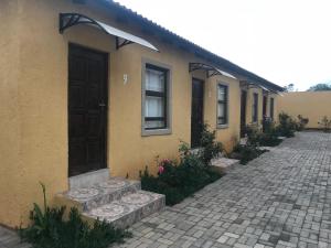 a yellow house with a door and a brick driveway at Kanyane Lodge in Jane Furse