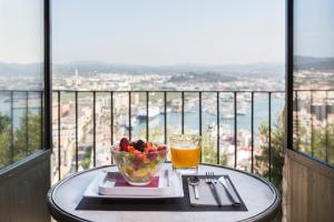 a table with a bowl of fruit and a glass of orange juice at Hotel La Torre del Canonigo - Small Luxury Hotels in Ibiza Town