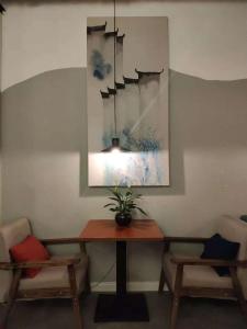 uma mesa de jantar com duas cadeiras e um vaso de plantas em Suzhou Blue Gate Youth Hostel em Suzhou