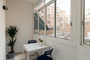 バルセロナにあるApartamento Eixample Sants Estacióの窓付きの客室で、白いテーブルと椅子が備わります。