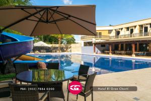 - une table avec un parasol à côté de la piscine dans l'établissement Hotel El Gran Chortí, à Esquipulas