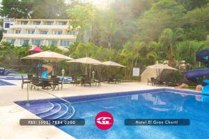 a swimming pool with chairs and umbrellas next to a hotel at Hotel El Gran Chort&iacute; in Esquipulas