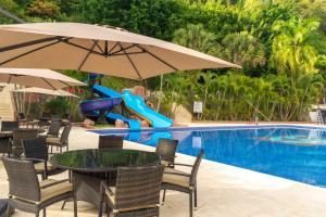 a pool with a table and umbrella and a slide at Hotel El Gran Chort&iacute; in Esquipulas