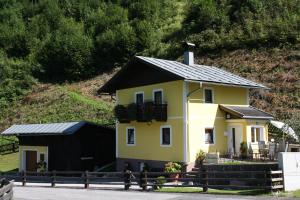 ein gelbes Haus mit schwarzem Dach in der Unterkunft Ferienhaus Christine in Taxenbach
