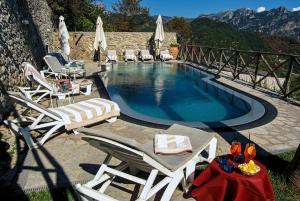 a swimming pool with lounge chairs and a table and a table at Garden Hotel in Ravello