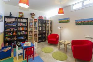 une bibliothèque avec des chaises rouges, une table et des étagères dans l'établissement Apartamentos Turísticos Playa de Tapia, à Tapia de Casariego