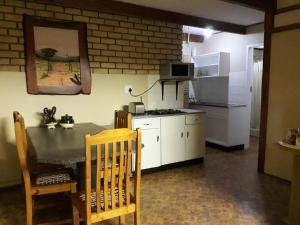 a kitchen with a table and a stove and a refrigerator at Die Plasie Two-Bedroom Flat in Hartbeespoort
