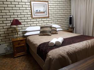 a bedroom with a bed with two pillows on it at Die Plasie Two-Bedroom Flat in Hartbeespoort