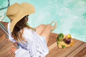 una donna con un cappello seduta accanto alla piscina di Hotel Paris a Rimini