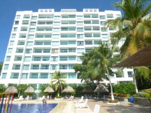 a large white building with palm trees and a swimming pool at Costa Azul Suites 905 in Santa Marta