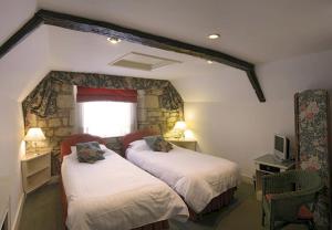 a bedroom with two beds and a stone wall at Bath Place Hotel in Oxford
