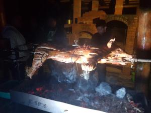 a man standing next to a large animal over a fire at Pensiunea Casiana in Ciulpăz