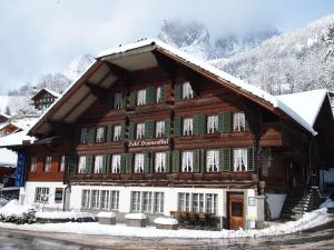 a large wooden building with snow on it at Hotel Simmental in Boltigen