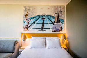 a bed in a hotel room with a pool picture on the wall at Novotel Metz Amnéville in Maizières-lès-Metz