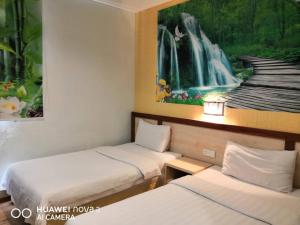 two beds in a room with a waterfall painting on the wall at Mega Inn in Kuching