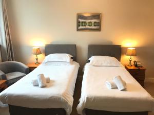 2 Betten in einem Hotelzimmer mit Handtüchern darauf in der Unterkunft Keswick Park Hotel in Keswick