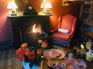 a living room with a fireplace and a table with flowers at B&B Aux Quatre Bonniers in Olne
