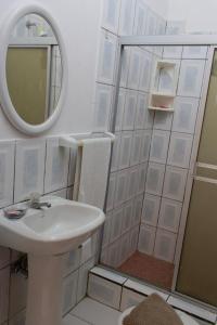ein Bad mit einem Waschbecken, einem Spiegel und einer Dusche in der Unterkunft El Paraiso in Montañita
