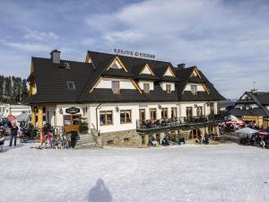 a building with a group of people in the snow at Karcma Hajnos Pokoje in Białka Tatrzańska