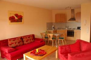a living room with two red couches and a table at Wein- und Gästehaus Genetsch in Lieser