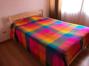 Una cama con una manta de colores encima. en Casa campestre Isabelita, en Tibasosa