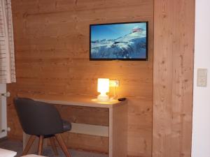 Zimmer mit einem Schreibtisch und einem TV an der Wand in der Unterkunft Haus Christopherus in Klösterle am Arlberg