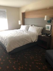 Cette chambre comprend un grand lit avec des draps et des oreillers blancs. dans l'établissement Holiday Inn Hotel & Suites - Mount Pleasant, an IHG Hotel, à Mount Pleasant