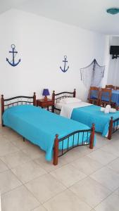 two beds with blue sheets in a room at Tinos apartments Zalonis in Agios Ioannis