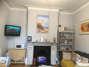 a living room with a fireplace and a tv at Cliftonville House in Whitstable