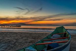a boat sitting on the beach at sunset at Innbox - Canasvieiras in Florianópolis