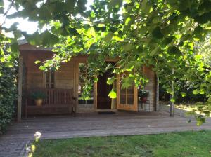 a small wooden cabin with a wooden porch at B&B Zeijen in Zeyen