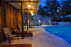 a patio with chairs and a swimming pool at night at Hotel & Suites Oasis Bacalar in Bacalar