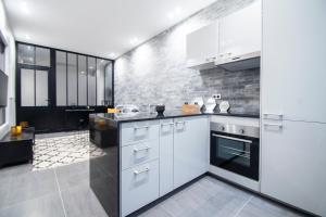 uma cozinha com armários brancos e um forno com placa de fogão em Dreamyflat - Loft Louvre em Paris