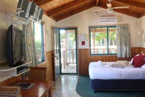 a bedroom with a bed and a tv and a table at Lani's Holiday Island in Forster